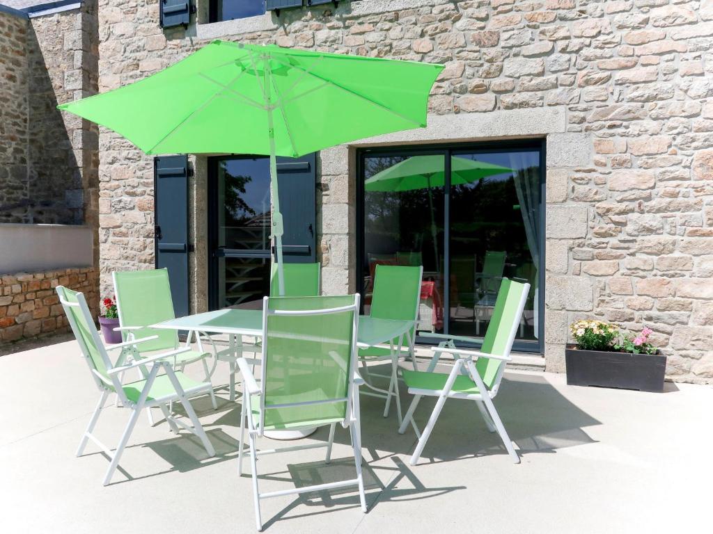 een tafel en stoelen met een groene parasol bij Holiday Home Ty Angèle - PLC239 by Interhome in Plouescat