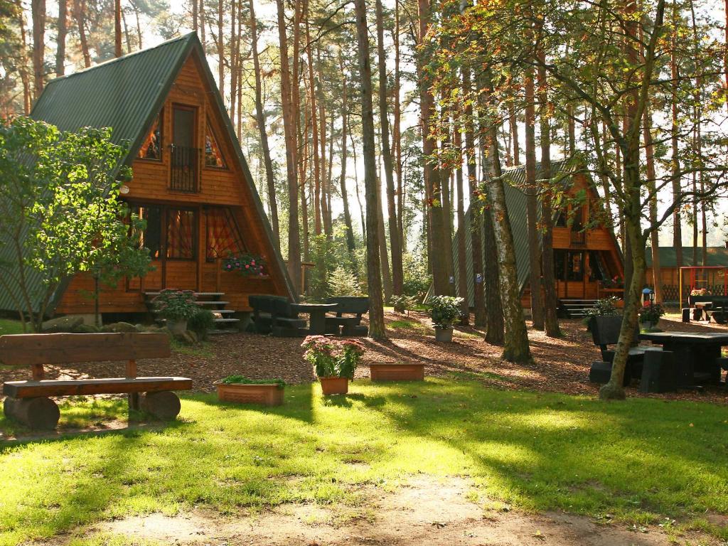 eine Hütte im Wald mit einem Picknicktisch und Bänken in der Unterkunft Chalet Nepumuk-3 by Interhome in Arendsee