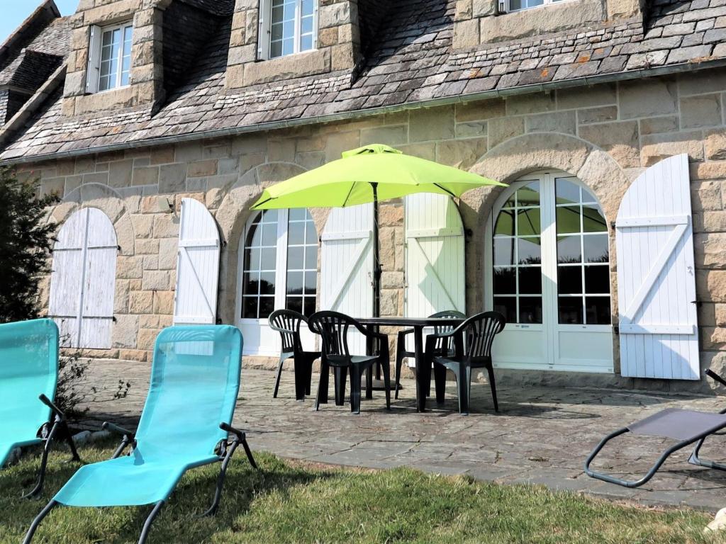 une table avec des chaises et un parasol devant un bâtiment dans l'établissement Holiday Home La Mouette by Interhome, à Kertissiec