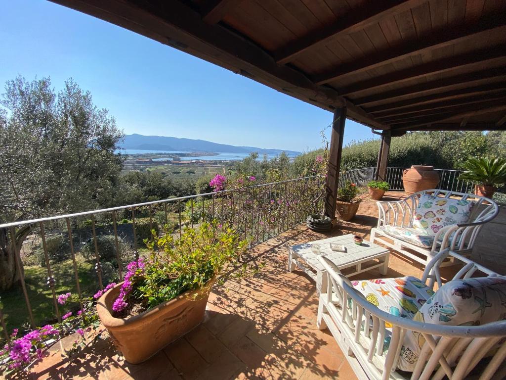 a patio with chairs and flowers on a balcony at Casa ai Poggi dell'Argentario in Orbetello