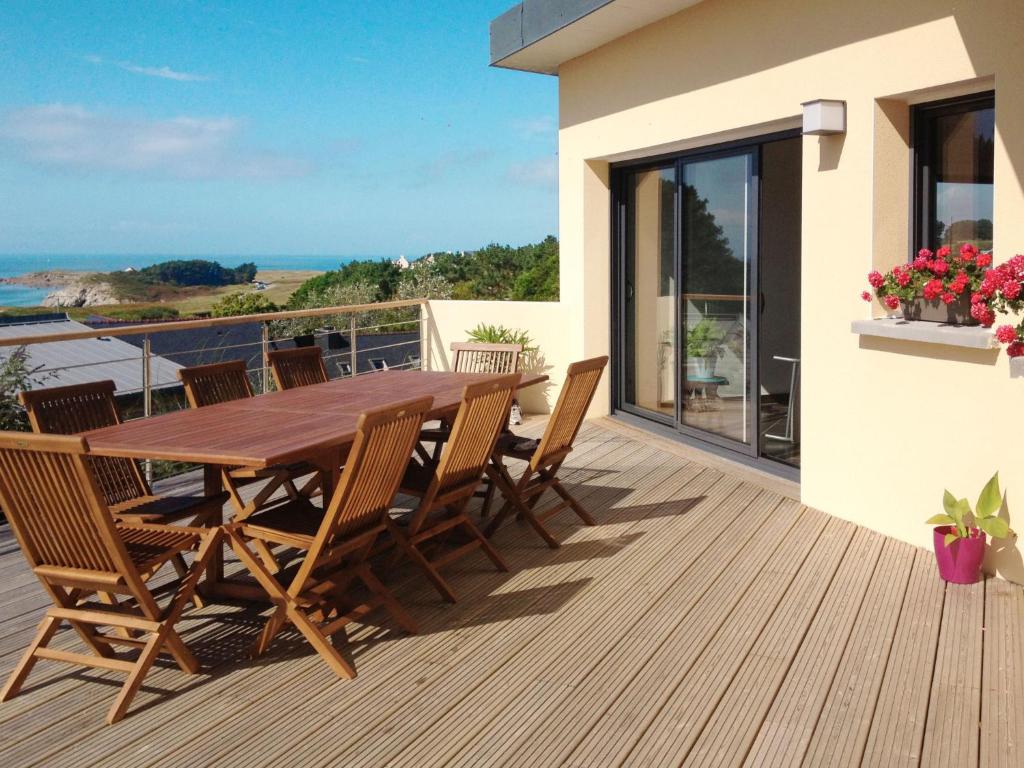 a wooden deck with a wooden table and chairs at Holiday Home Maison de Plain Pied - Vue Mer - TRP106 by Interhome in Kergador