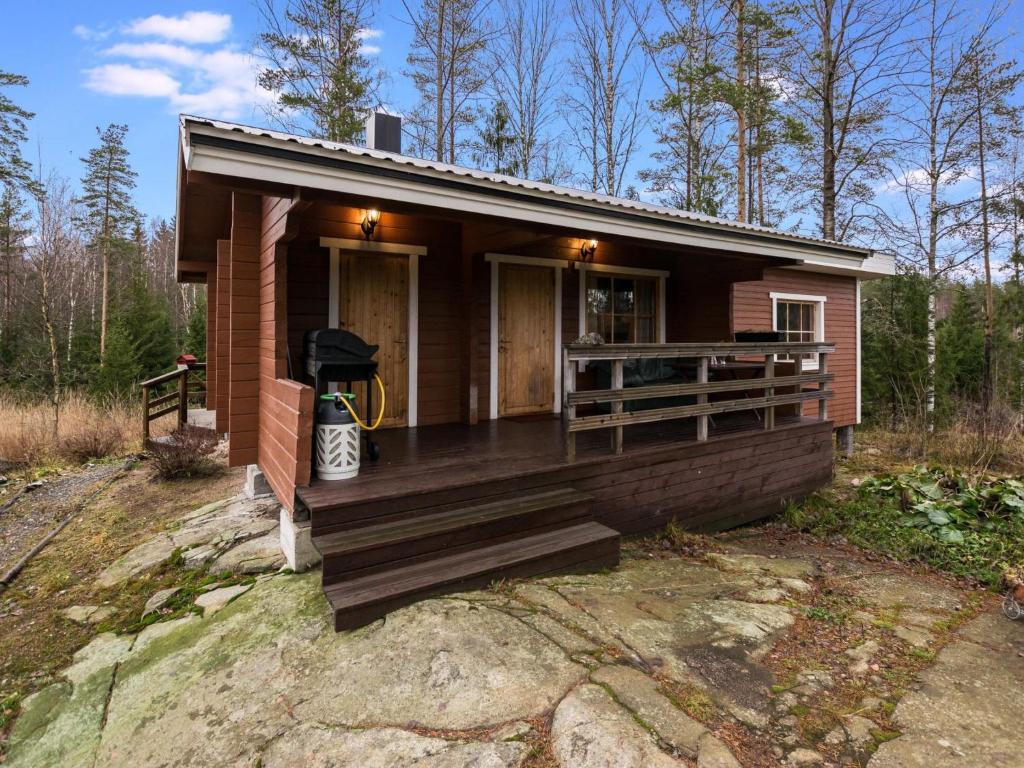 a small wooden house with a porch and a yard at Holiday Home Mäntymäki by Interhome in Kelkala