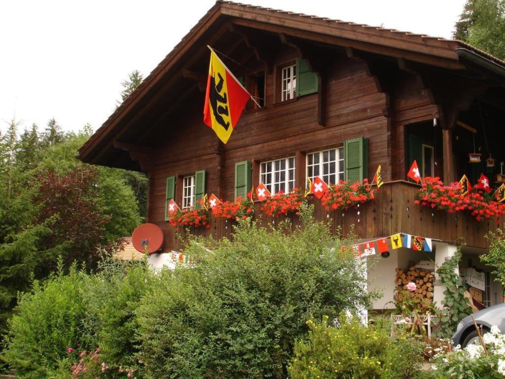 a wooden house with flowers in front of it at Apartment Bach by Interhome in Lenk
