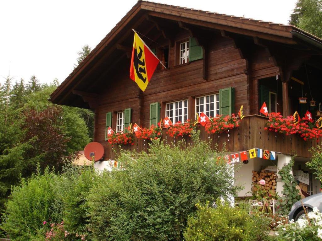 ein Holzhaus mit Blumen davor in der Unterkunft Apartment Bach by Interhome in Lenk im Simmental