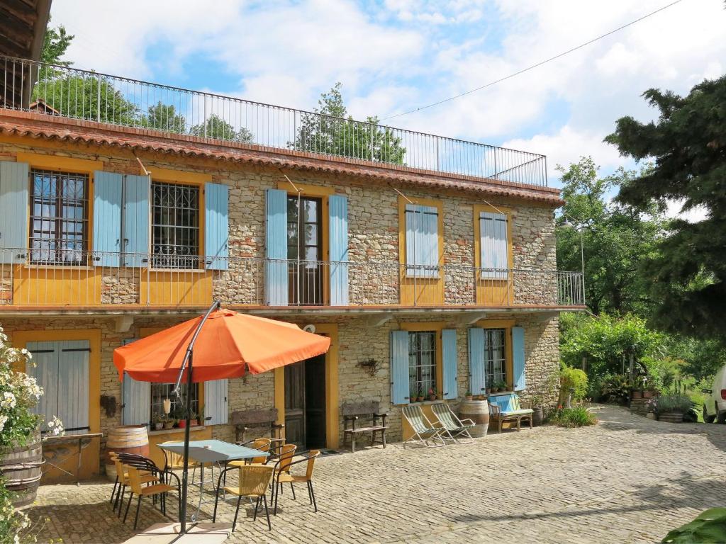 an orange umbrella sitting in front of a building at Holiday Home La Rovere by Interhome in Cossano Belbo