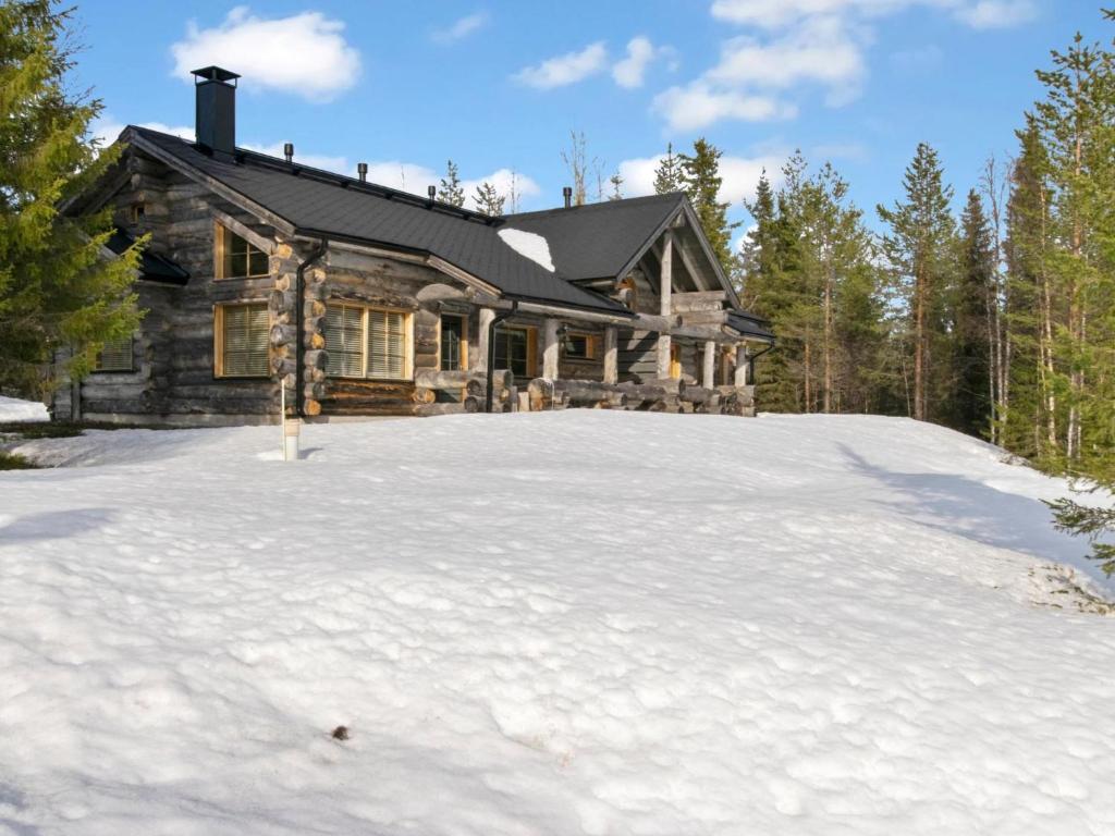 a log cabin in the snow in front of a house at Holiday Home Peikkola by Interhome in Ruka