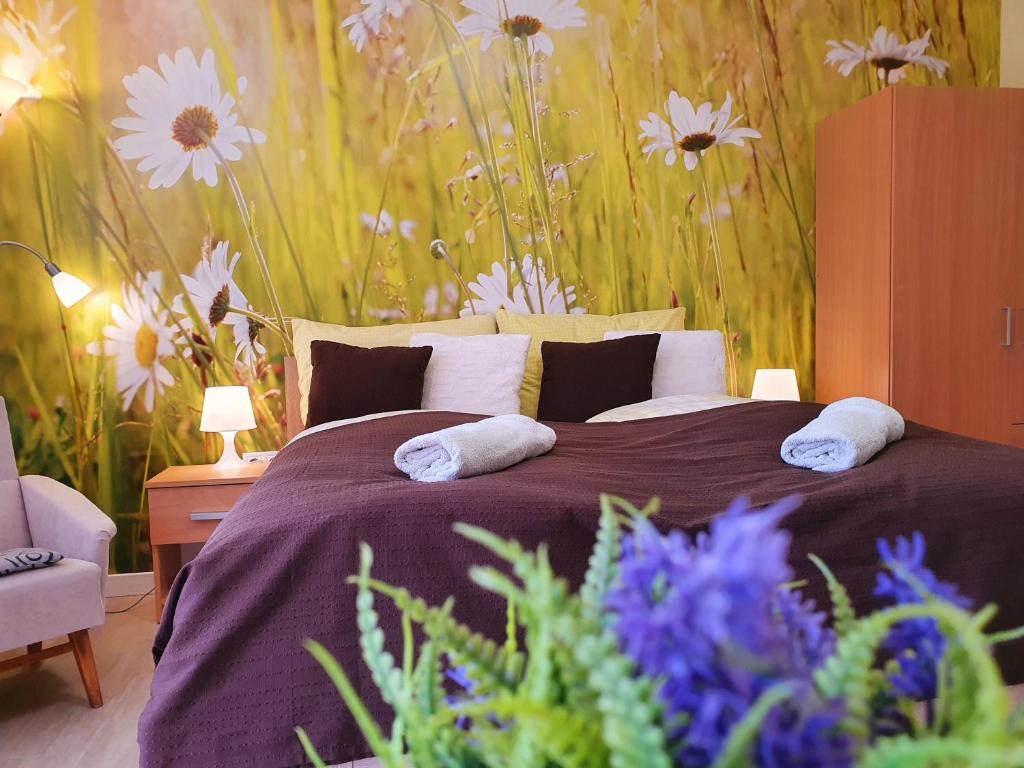 a bedroom with a large bed with flowers on the wall at Lavendel apartments in Hévíz