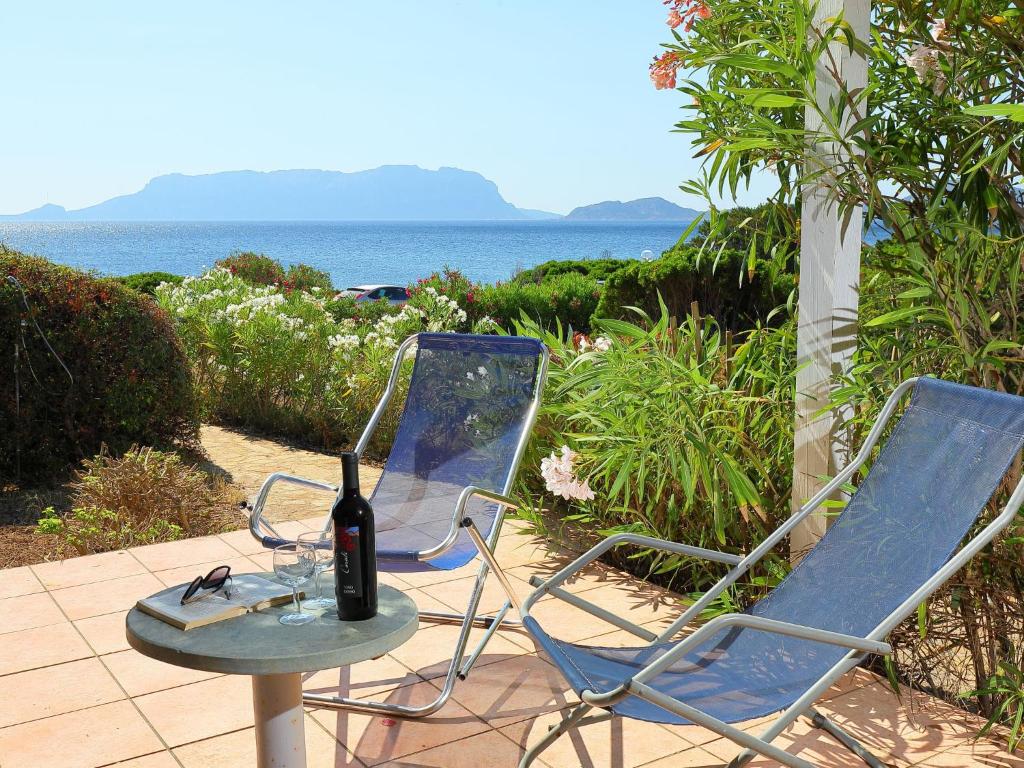 2 sedie e un tavolo con una bottiglia di vino di Apartment Vista Tavolara 2 by Interhome a Pittulongu