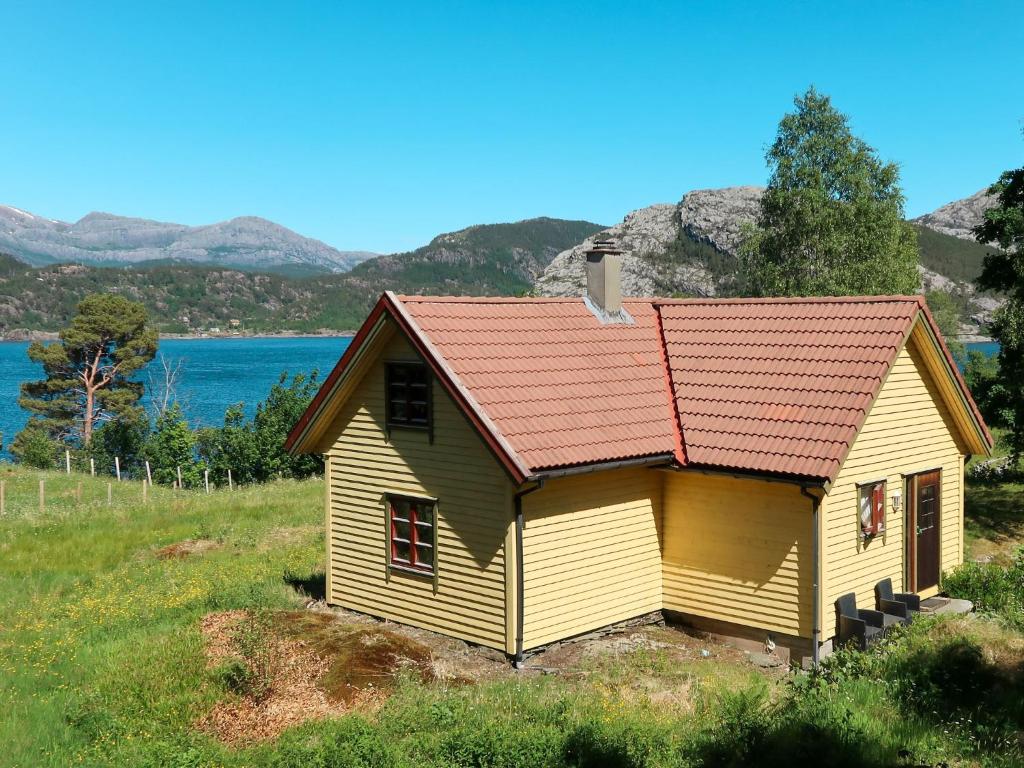 una casa amarilla con techo rojo en un campo en Holiday Home Rabbane - FJS504 by Interhome, en Nyttingsnes
