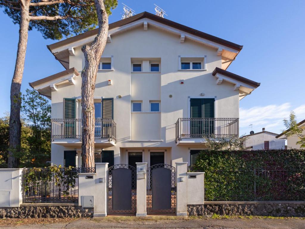 biały dom z płotem i drzewami w obiekcie Apartment Michelangelo II by Interhome w mieście Marina di Pietrasanta