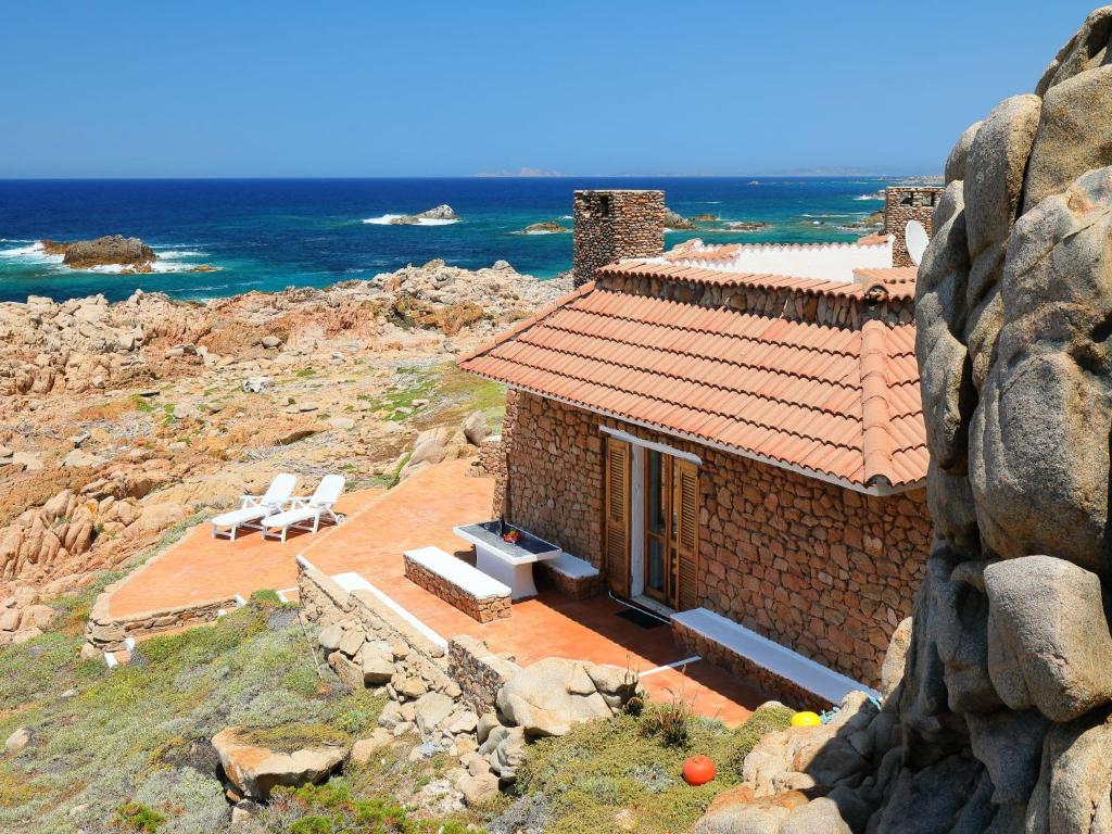 una casa in mattoni con due sedie e l'oceano di Holiday Home La Cala - VGM615 by Interhome a Aglientu