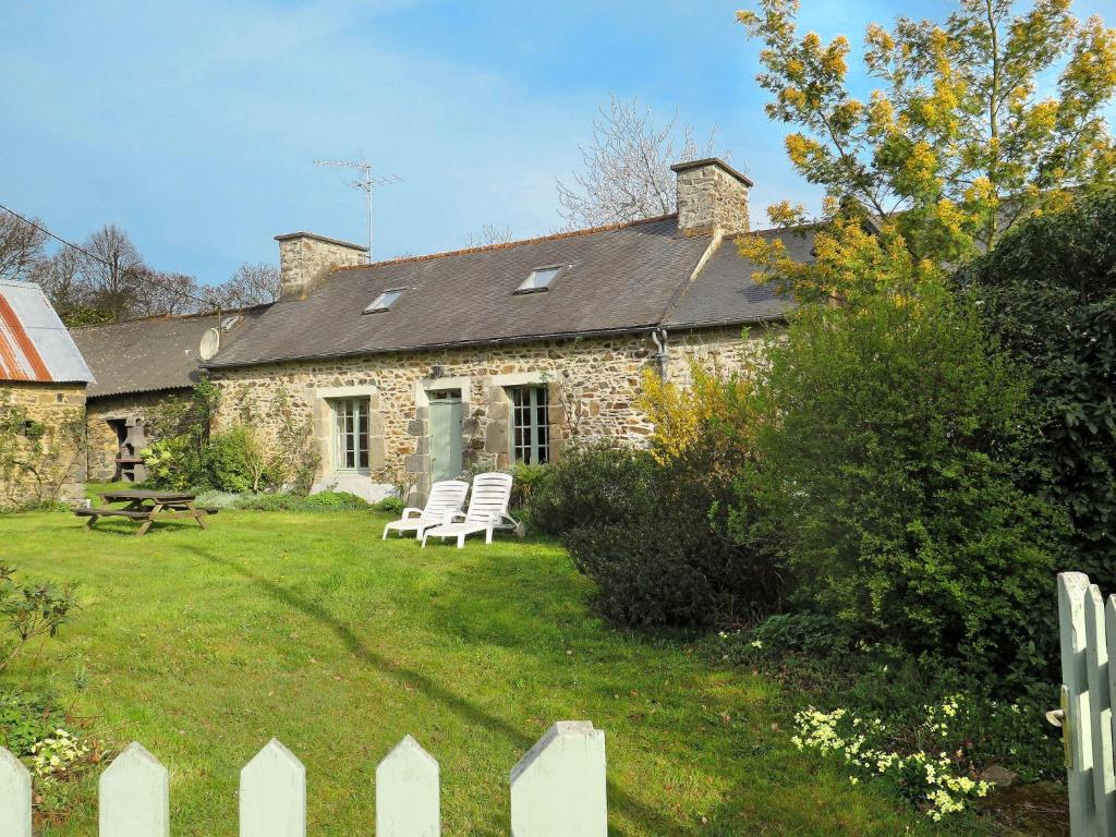 une maison en pierre avec 2 chaises blanches dans une cour dans l'établissement Holiday Home Gîte des Oiseaux by Interhome, à Plouha