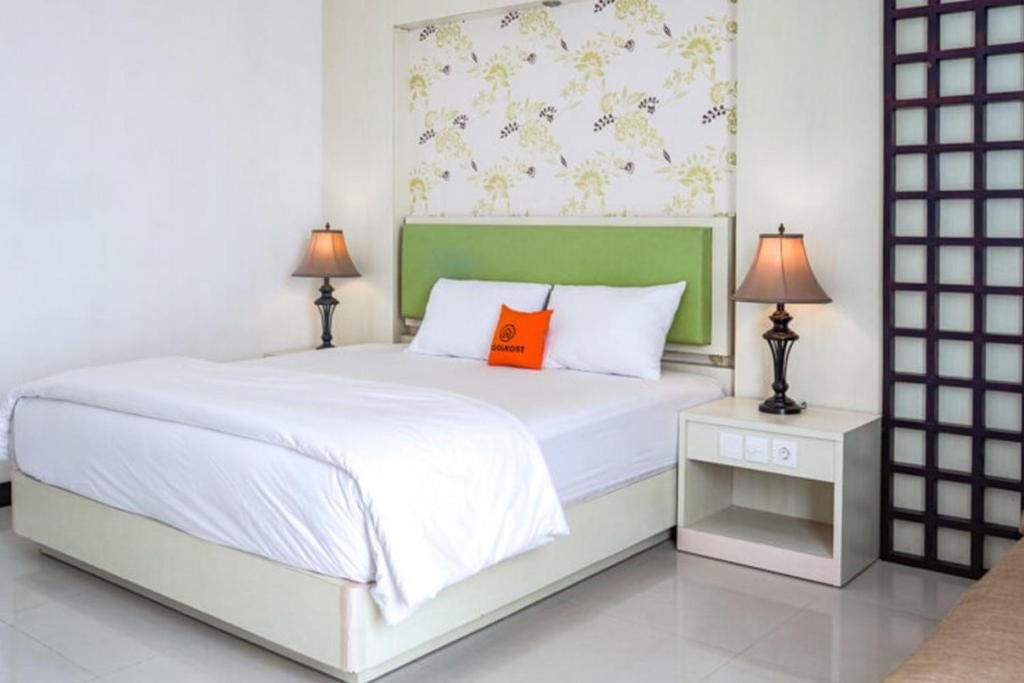 库塔KoolKost at Bypass Jimbaran - Minimum Stay 30 Nights的卧室配有白色床和橙色枕头