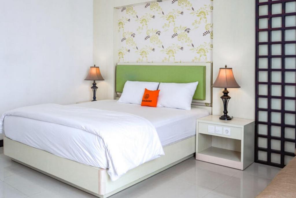 a bedroom with a white bed with an orange pillow at KoolKost @ Bypass Jimbaran in Kuta