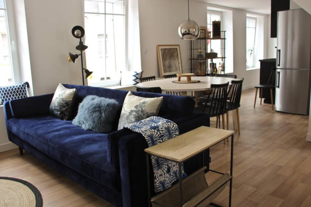 een woonkamer met een blauwe bank en een tafel bij A stylish apartment in the centre of town in Montreuil-sur-Mer