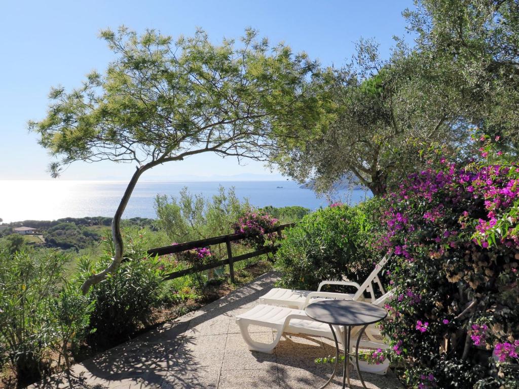 einen Tisch und einen Stuhl auf einer Terrasse mit Blumen in der Unterkunft Holiday Home Piccola Oasi-5 by Interhome in Capoliveri