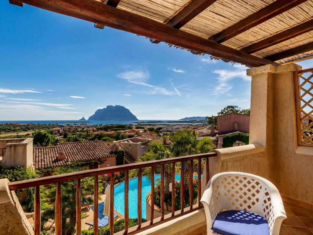a balcony with a view of a pool and mountains at Holiday Home Corbezzolo 9 - Vista Village by Interhome in Porto San Paolo
