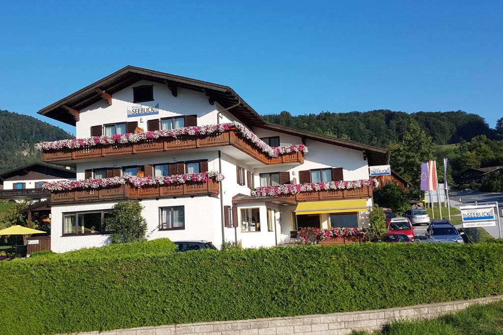 a large white building with flowers on the balconies at Frühstückspension Seeblick in Sankt Gilgen