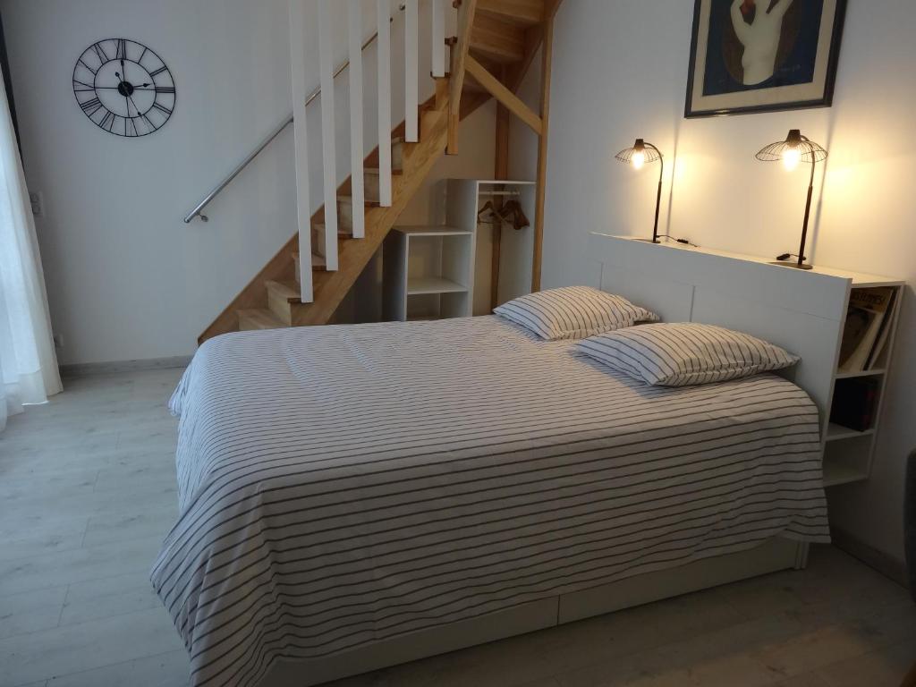 a bedroom with a bed with two pillows and a staircase at Les Petites Tuileries in Bray-sur-Seine