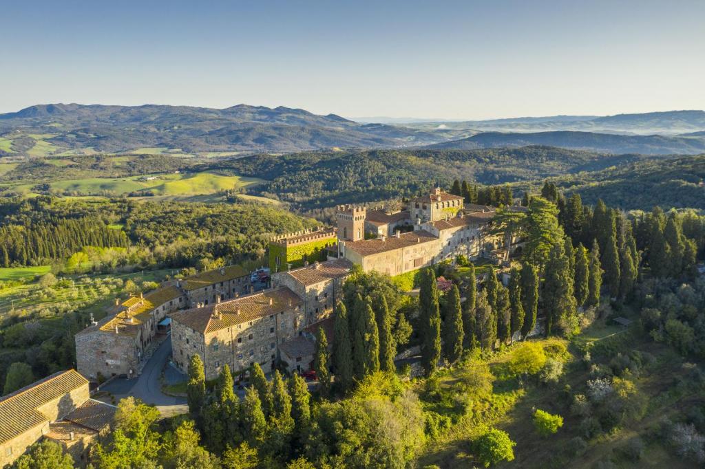 una vista aerea di un castello su una collina alberata di Castello Ginori Di Querceto a Querceto