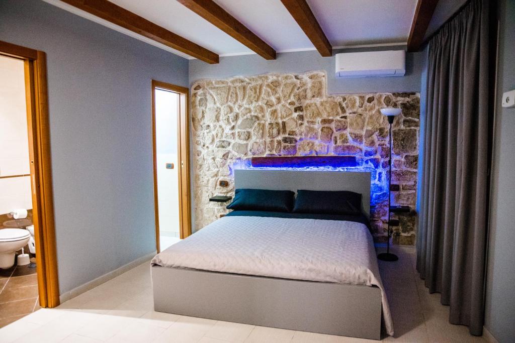 1 dormitorio con cama y pared de piedra en Dimora L'Etual en Bari