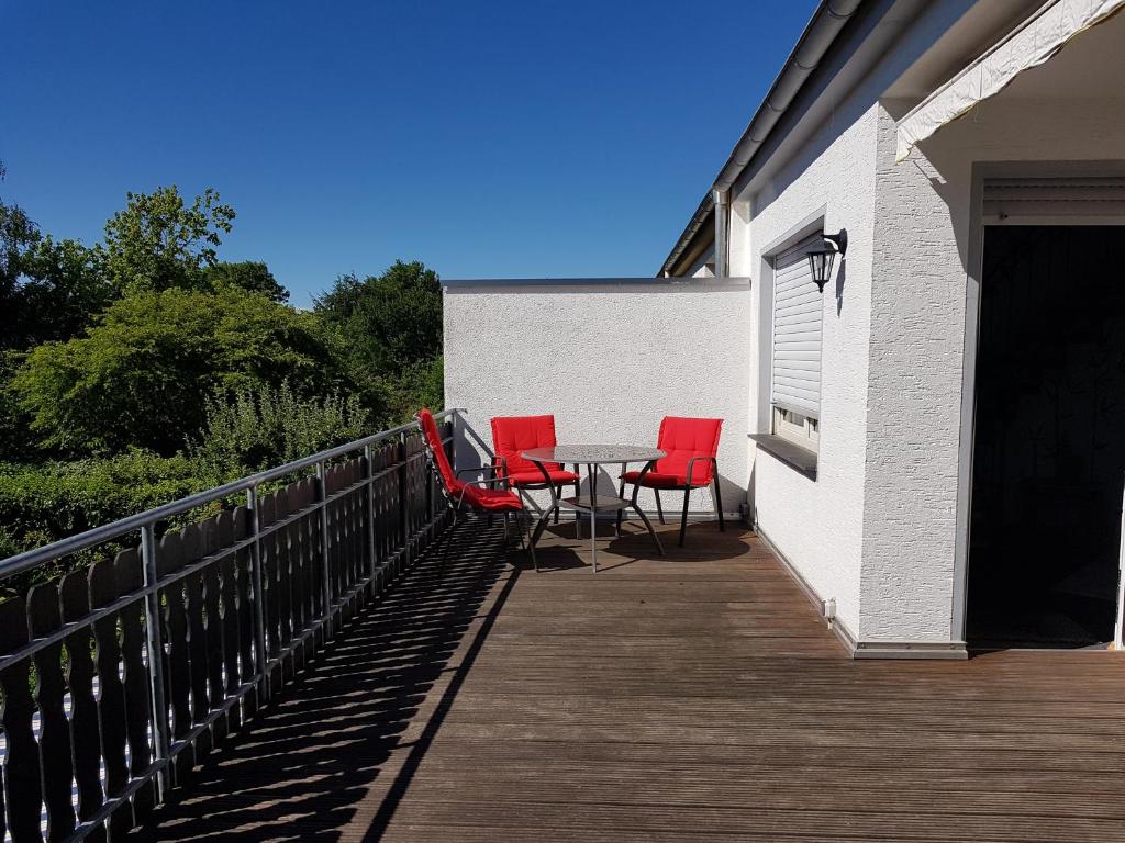 a patio with red chairs and a table on a deck at Himmelreich Nahne in Osnabrück