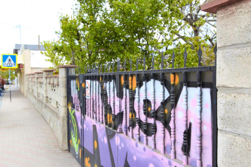 a fence with graffiti on it next to a sidewalk at Casa Ysa in Vama Veche