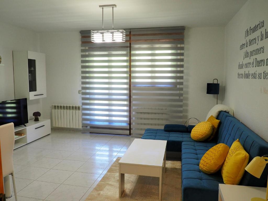 ein Wohnzimmer mit einem blauen Sofa und einem TV in der Unterkunft Apartamento Turístico Duero Niño in Molinos de Duero