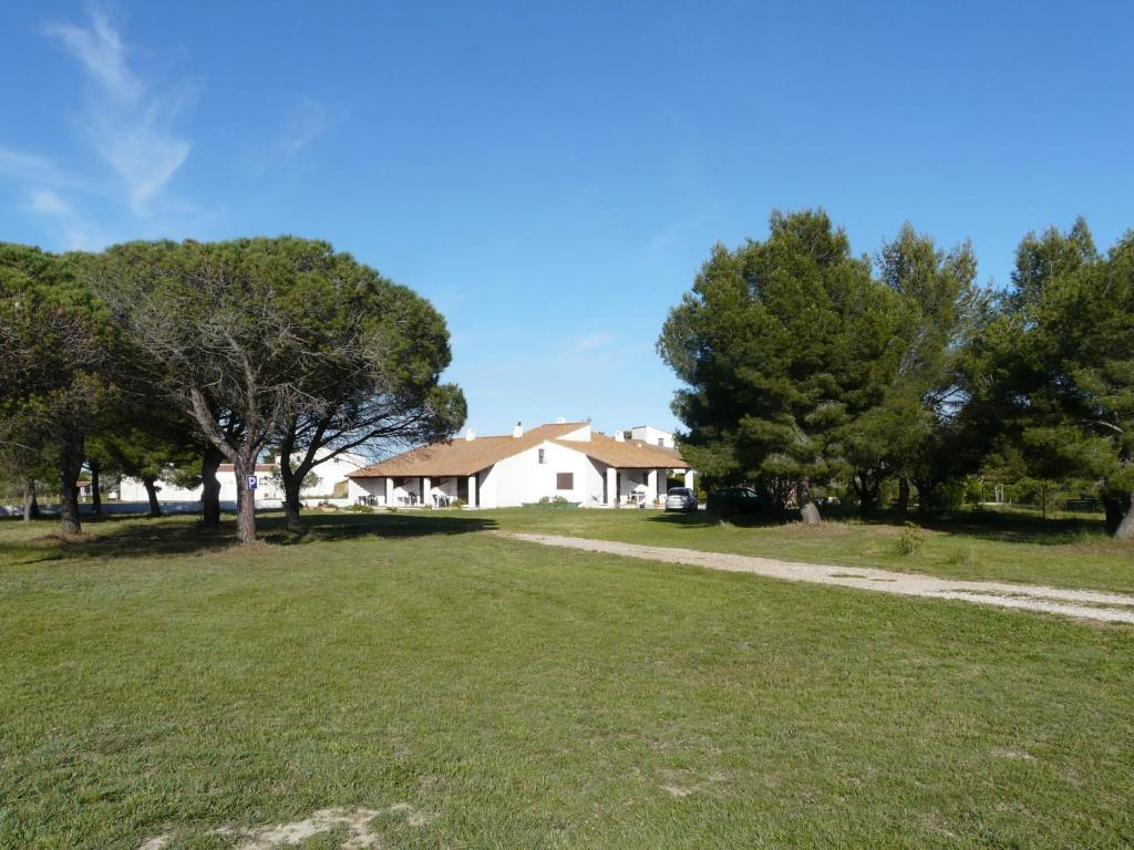 een wit huis met bomen en een grasveld bij Mas du Clos de la Barque in Saintes-Maries-de-la-Mer