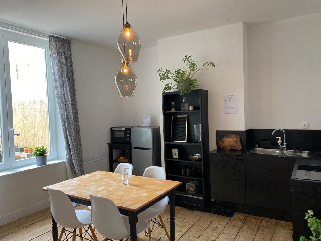 une salle à manger avec une table et des chaises ainsi qu'une cuisine dans l'établissement Le beffroi, à Calais