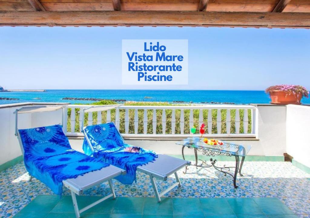 een balkon met 2 stoelen en een tafel en de oceaan bij Hotel La Scogliera in Ischia