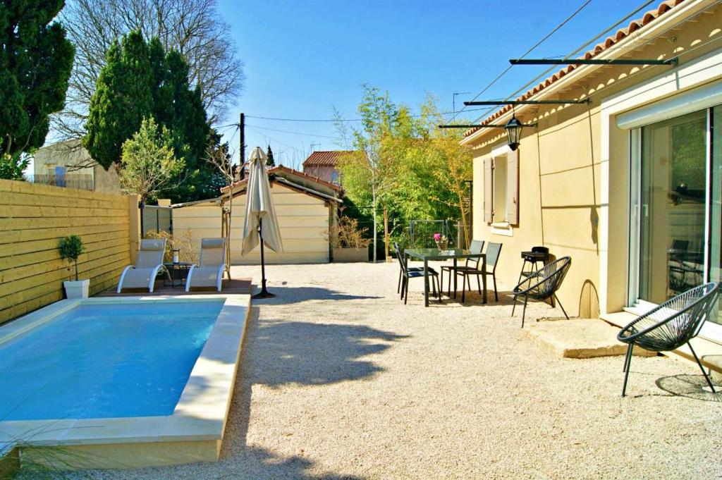 une cour avec une piscine, des chaises et une table dans l'établissement La Petite Maison en Provence, à Saint-Rémy-de-Provence