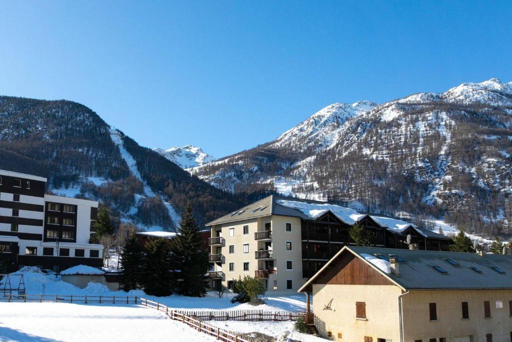 a group of buildings in the snow with mountains at Hôtel Mont Thabor Serre Chevalier in La Salle-les-Alpes