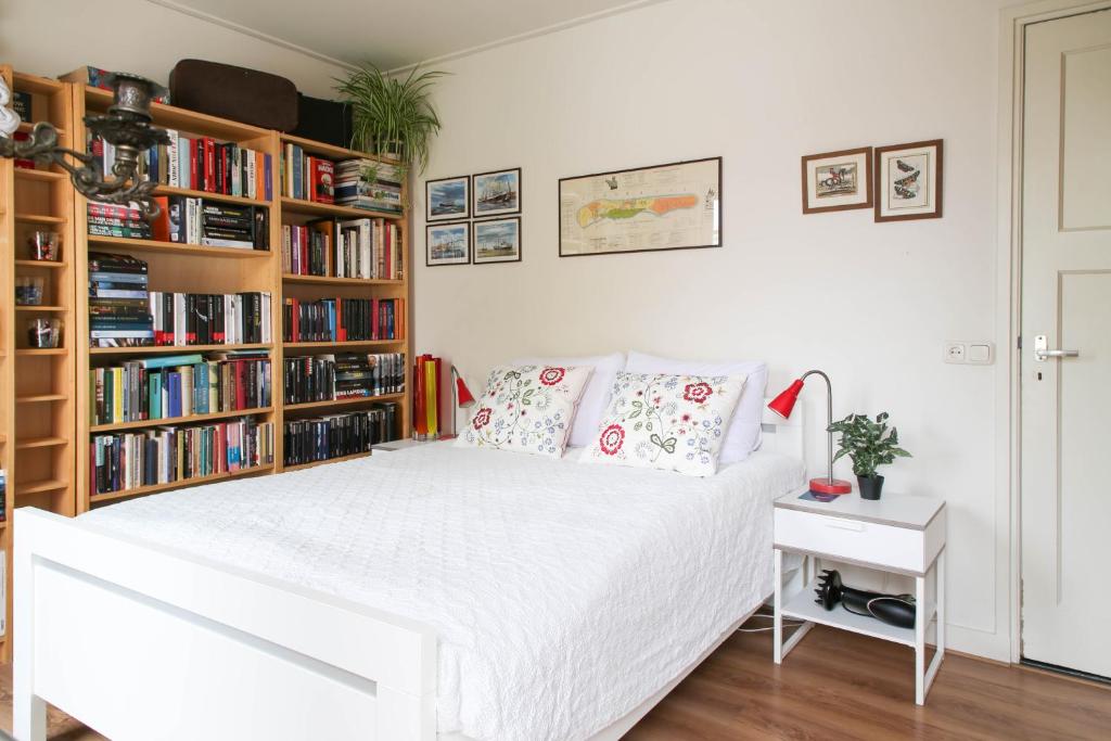 een wit bed in een kamer met boekenplanken bij Logement het Herenwaltje in Leeuwarden