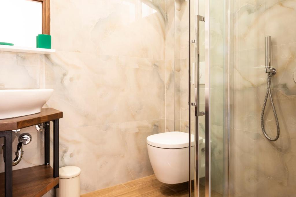 a bathroom with a toilet and a glass shower at sofia's cozy rooms in Himare