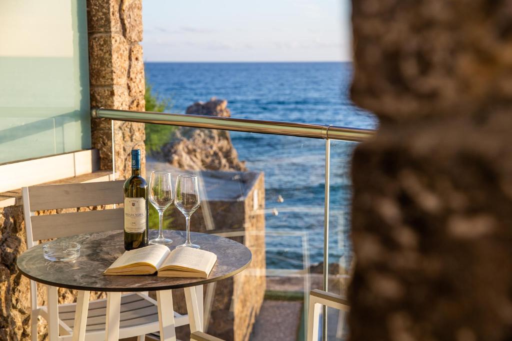 a table with a bottle of wine and two glasses at Black Rocks Family, Luxury Seafront Beach Maisonette in Agios Gordios