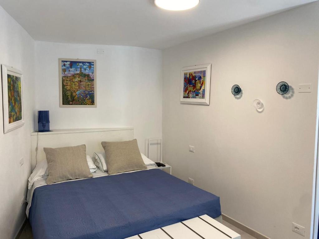a bedroom with a blue bed and paintings on the wall at Camere Nicolina 4 in Vernazza
