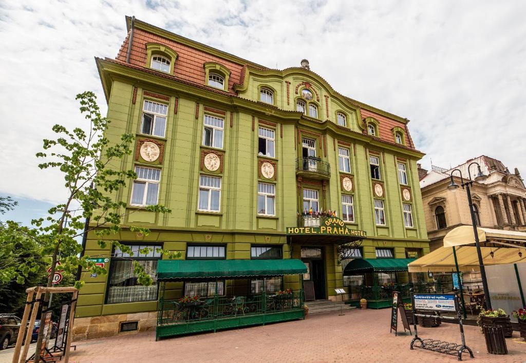a green and white building with a bus parked in front of it at Grand Hotel Praha in Jičín