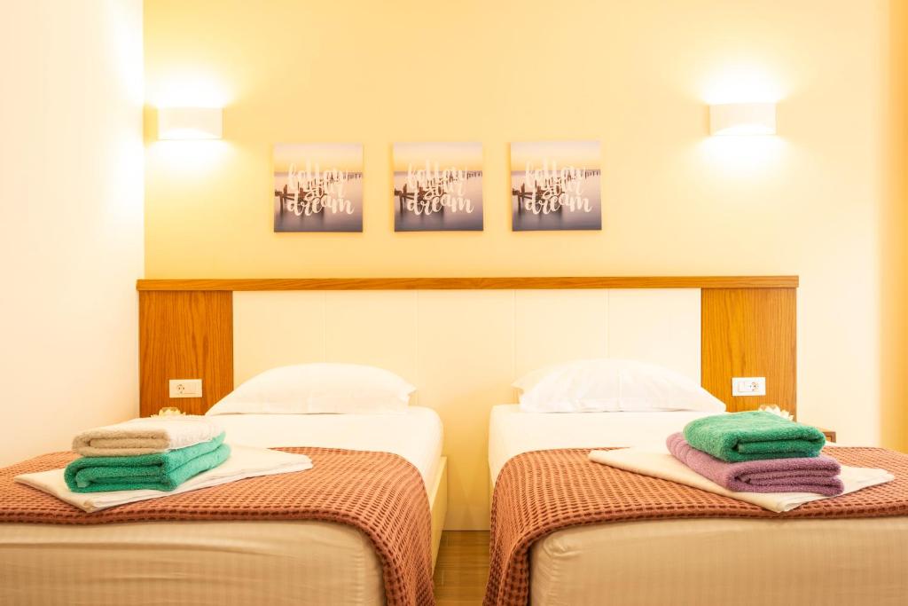 two beds in a hotel room with towels on them at sofia's cozy rooms in Himare