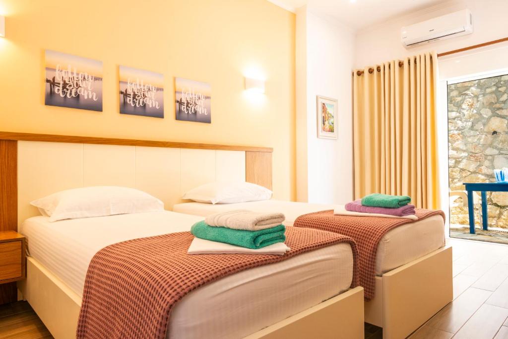 two beds in a hotel room with towels on them at sofia's cozy rooms in Himare