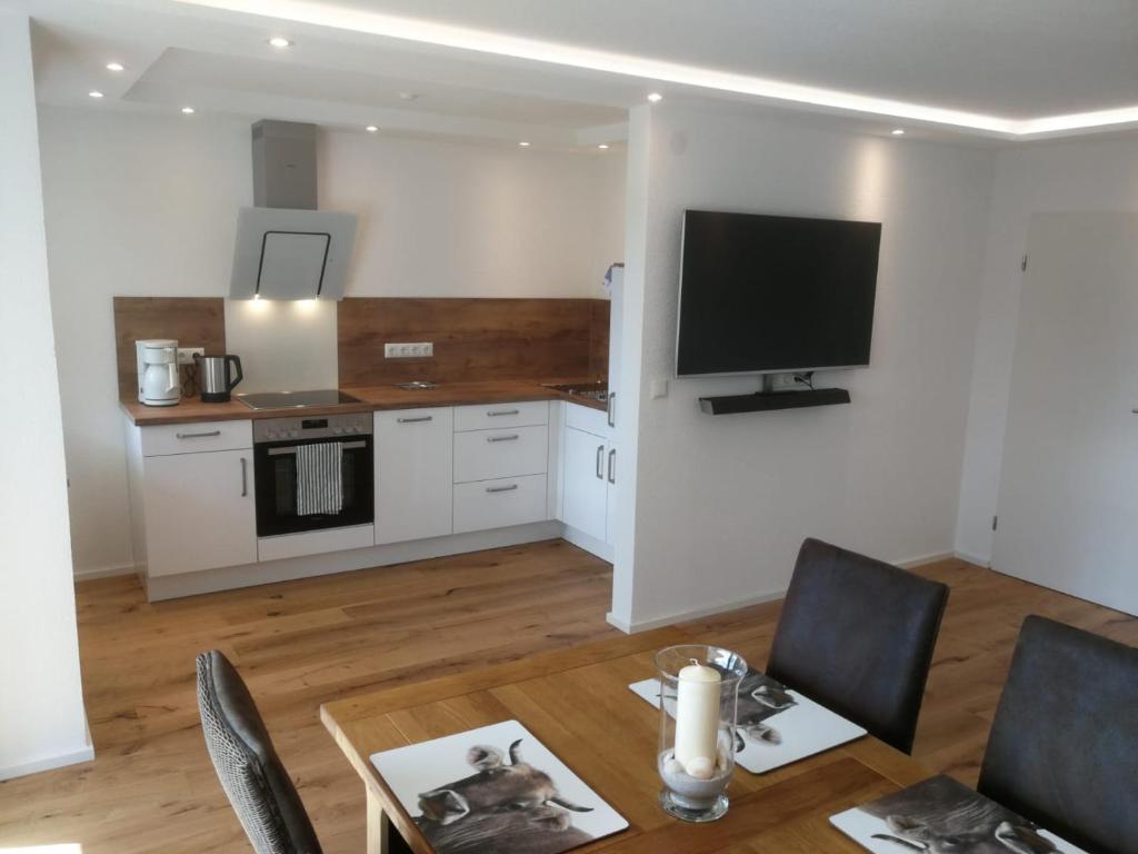 a living room with a table and a tv on the wall at Ferienwohnung am Bach in Missen-Wilhams