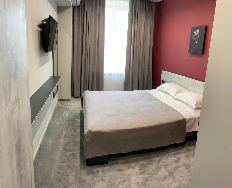 a bedroom with a bed and a red wall at Red Cube Hotel in Kamianets-Podilskyi