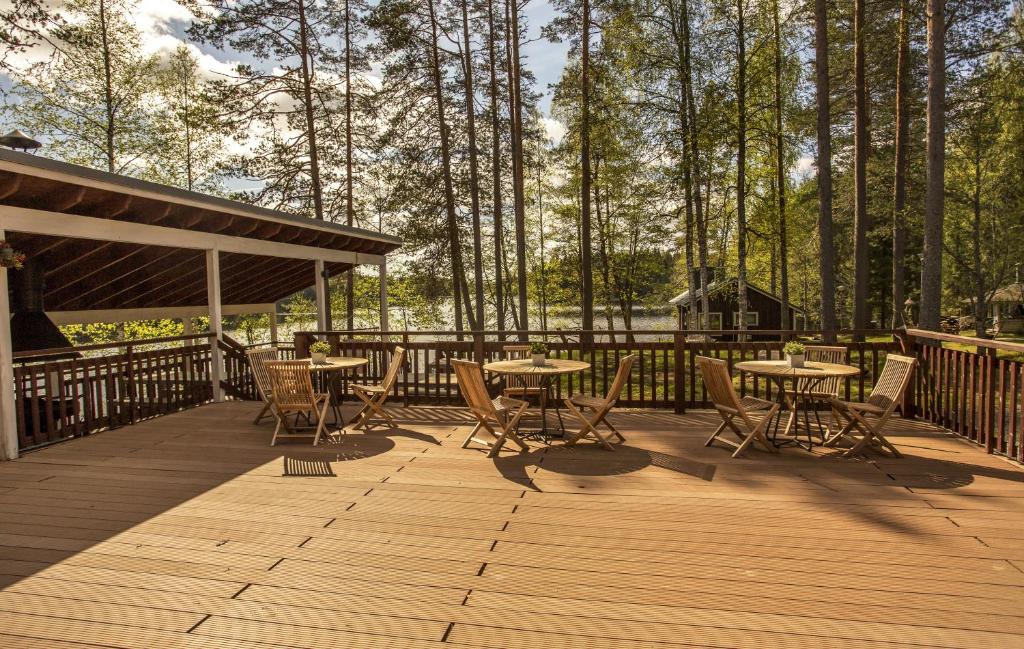 a wooden deck with tables and chairs and trees at Uniikki lomapaikka in Jämsä