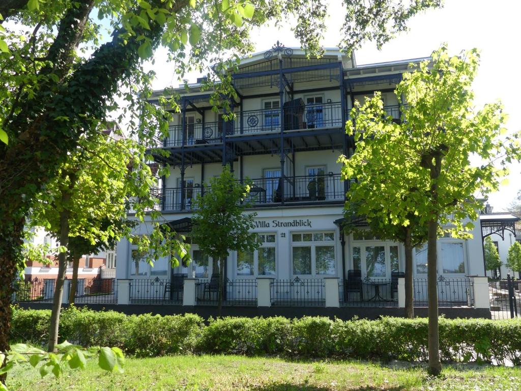 ビンツにあるFeWos direkt am Strand mit Balkon und teilweise mit Meerblick, Villa Strandblick, Binzの目の前に木々が植えられた白い大きな建物