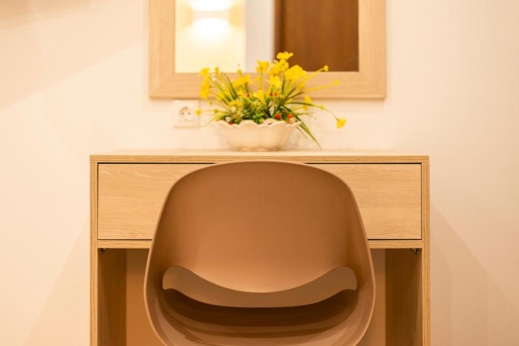 a desk with a chair and a vase with yellow flowers at sofia's cozy rooms in Himare