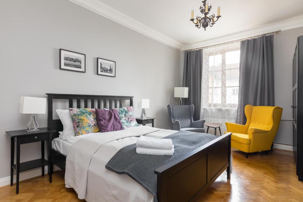a bedroom with a bed and a yellow chair at Jezuicka Old Town Pleasant Apartment in Warsaw
