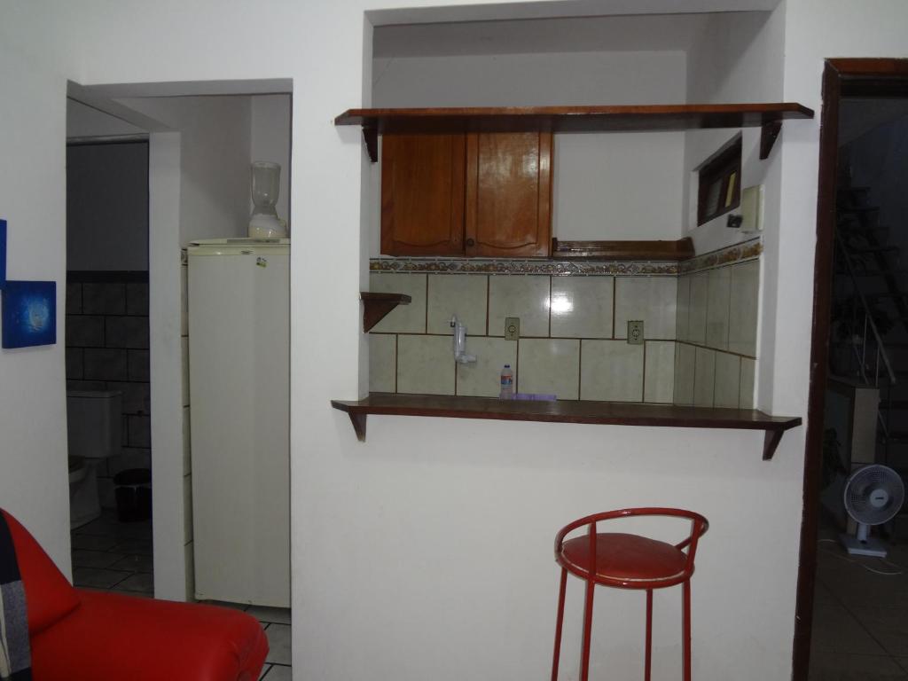 una cocina con una silla roja y un estante en la pared en Condomínio Mar Azul, en Salvador