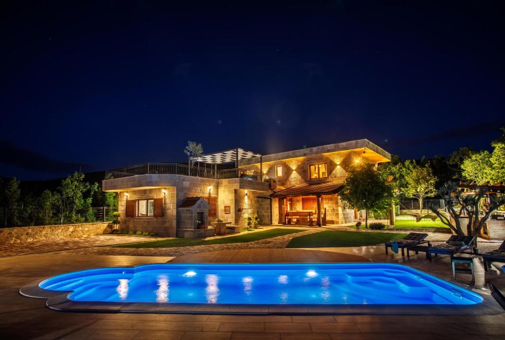 una casa con una piscina azul por la noche en Stone House Korita, en Otok