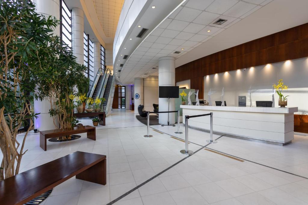 an office lobby with tables and potted plants at Mercure Sao Paulo Grand Plaza Paulista in Sao Paulo