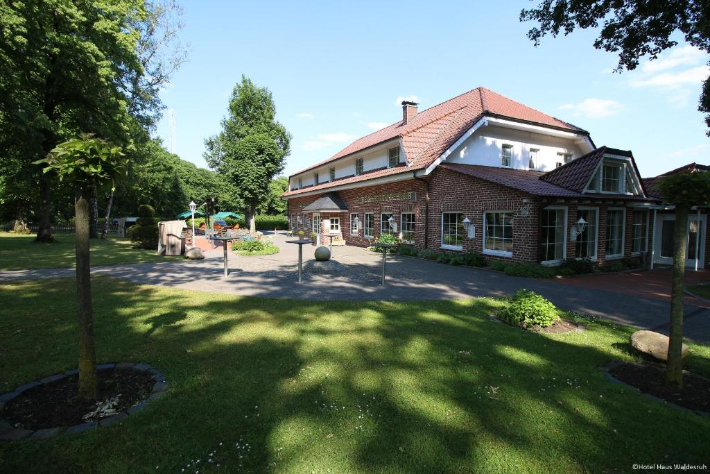 a large brick house with a tree in the yard at Hotel-Restaurant Haus Waldesruh in Borken